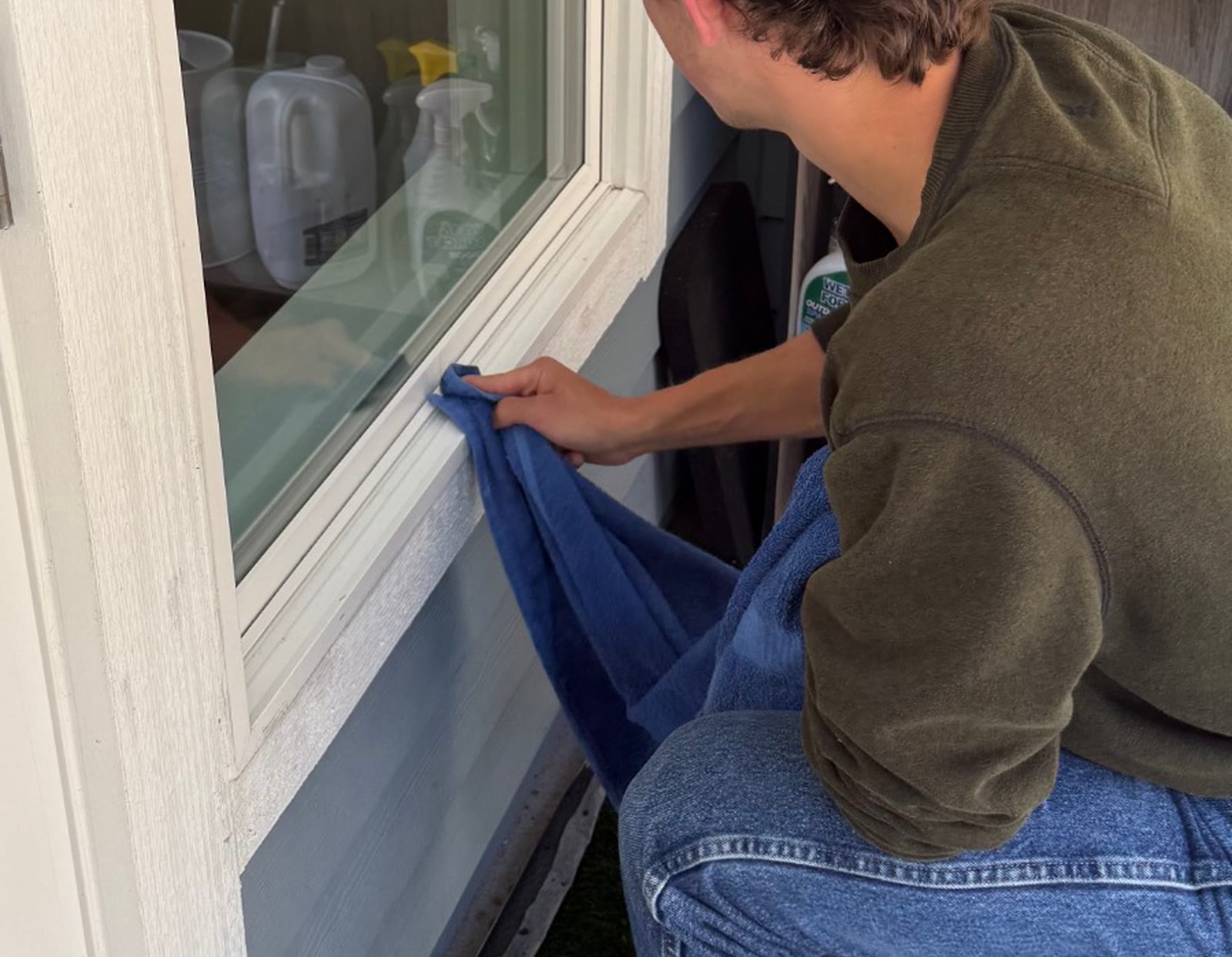 A close view of a residential window sill being wiped at ground level